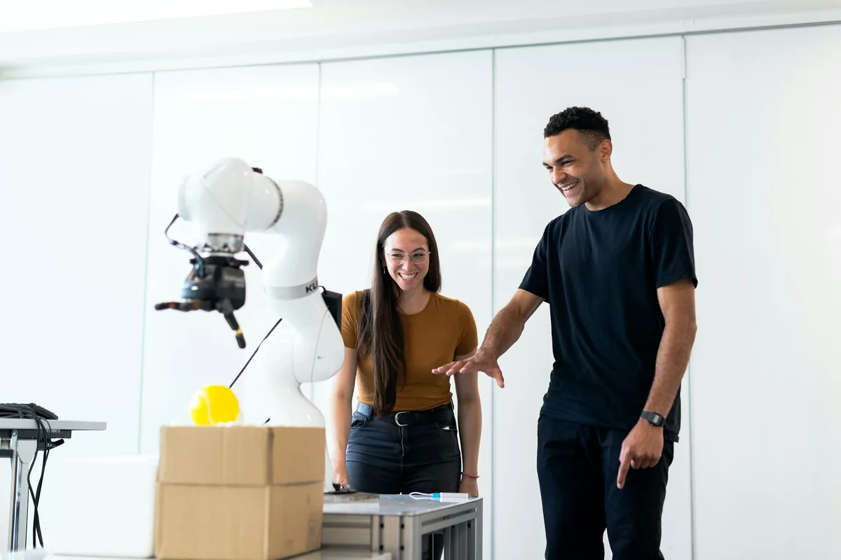 Engineers collaborating with a robotic arm